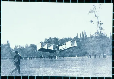 Fotografia do 14-Bis no ar sobre o campo de Bagatelle, com pessoas observando