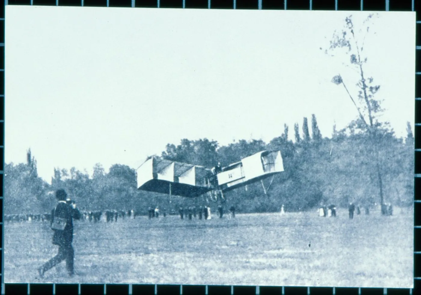 Fotografia do 14-Bis no ar sobre o campo de Bagatelle, com pessoas observando